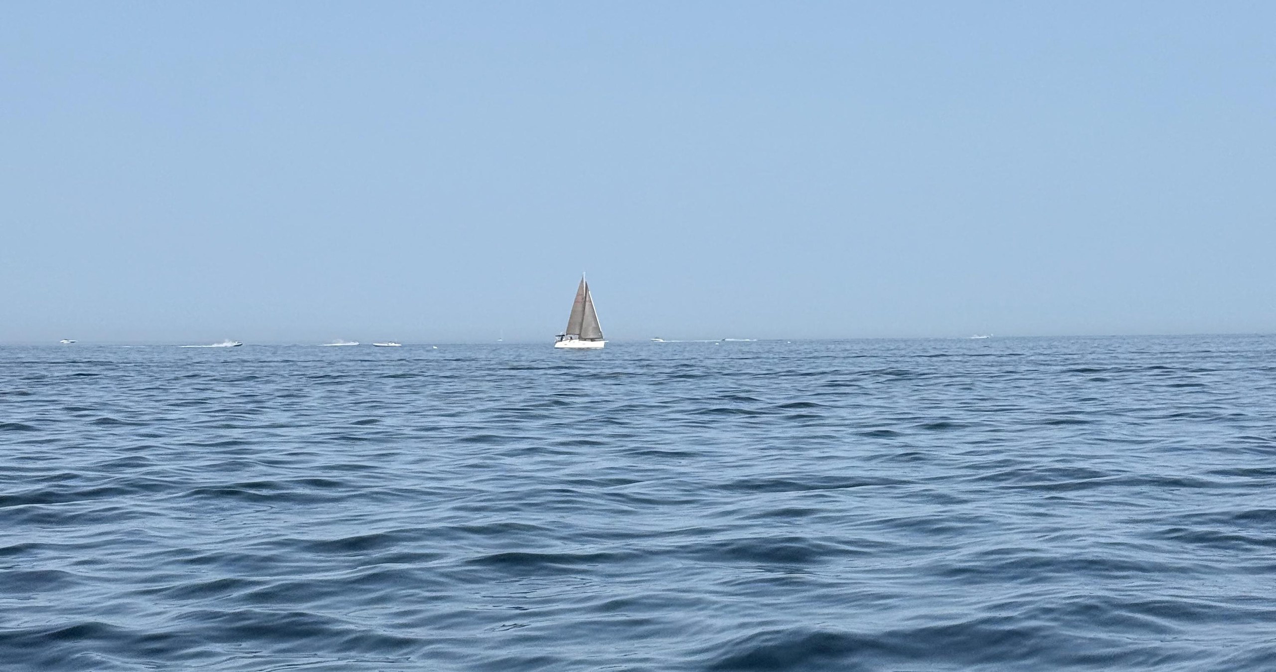 A lone sailboat on a calm, wide-open sea
