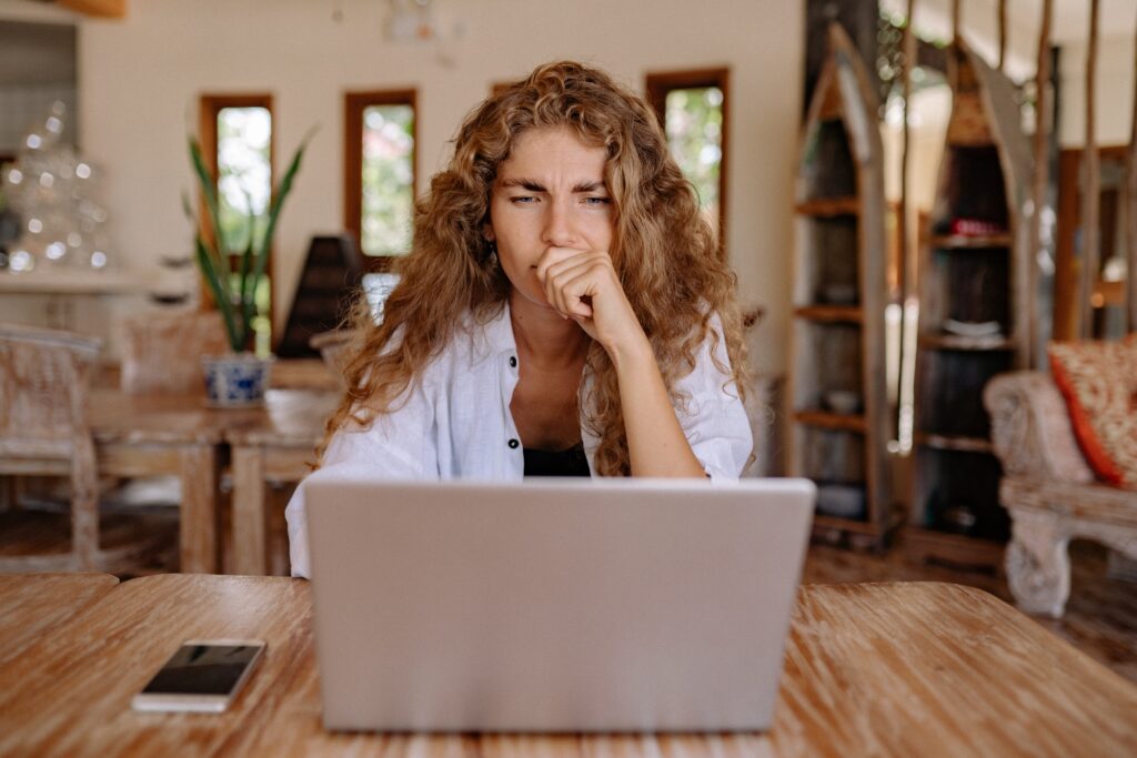 A woman is looking at a laptop thinking about a conflict at work