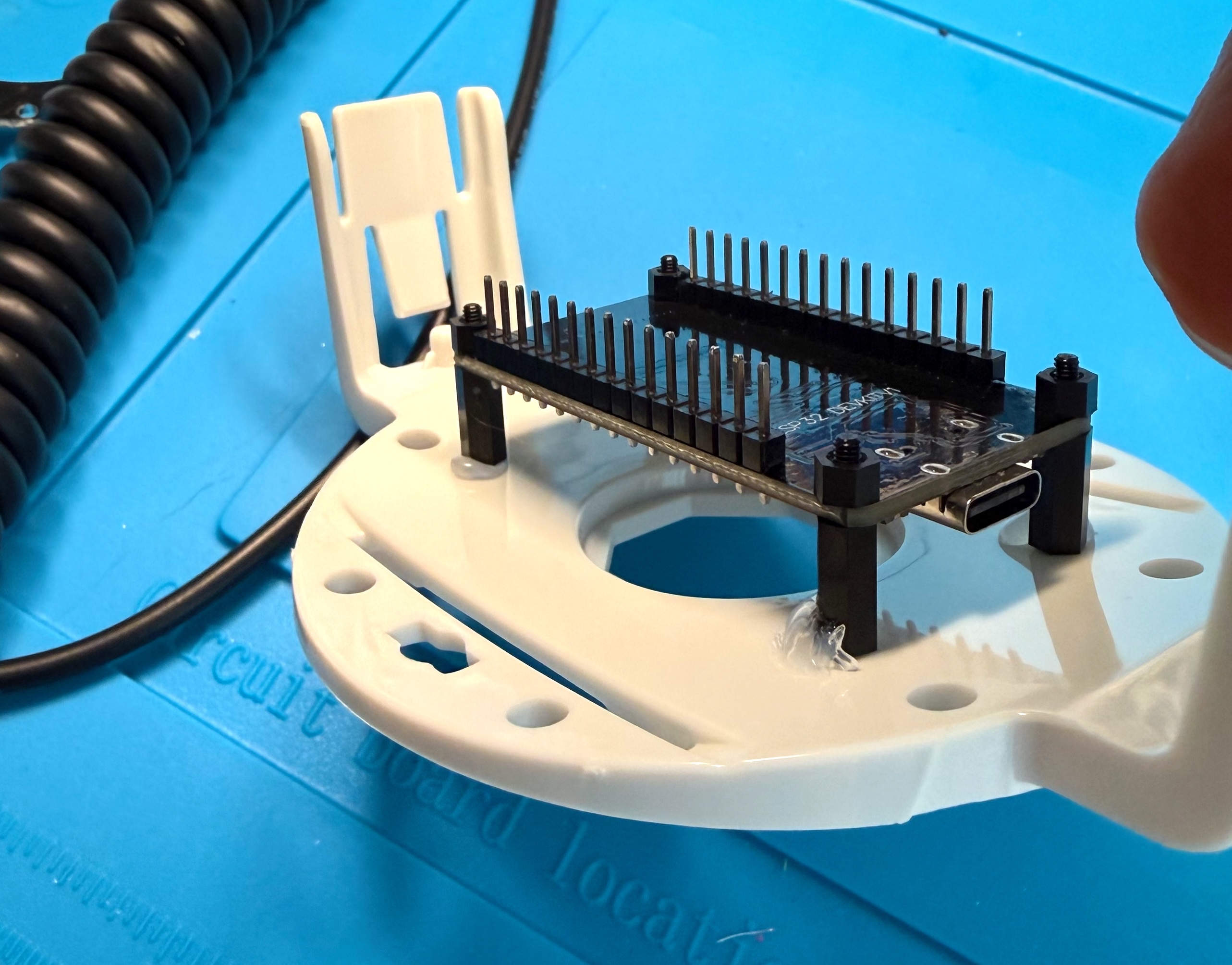 The ESP32 board raised on standoffs and hot-glued to the white plastic base plate from the toy