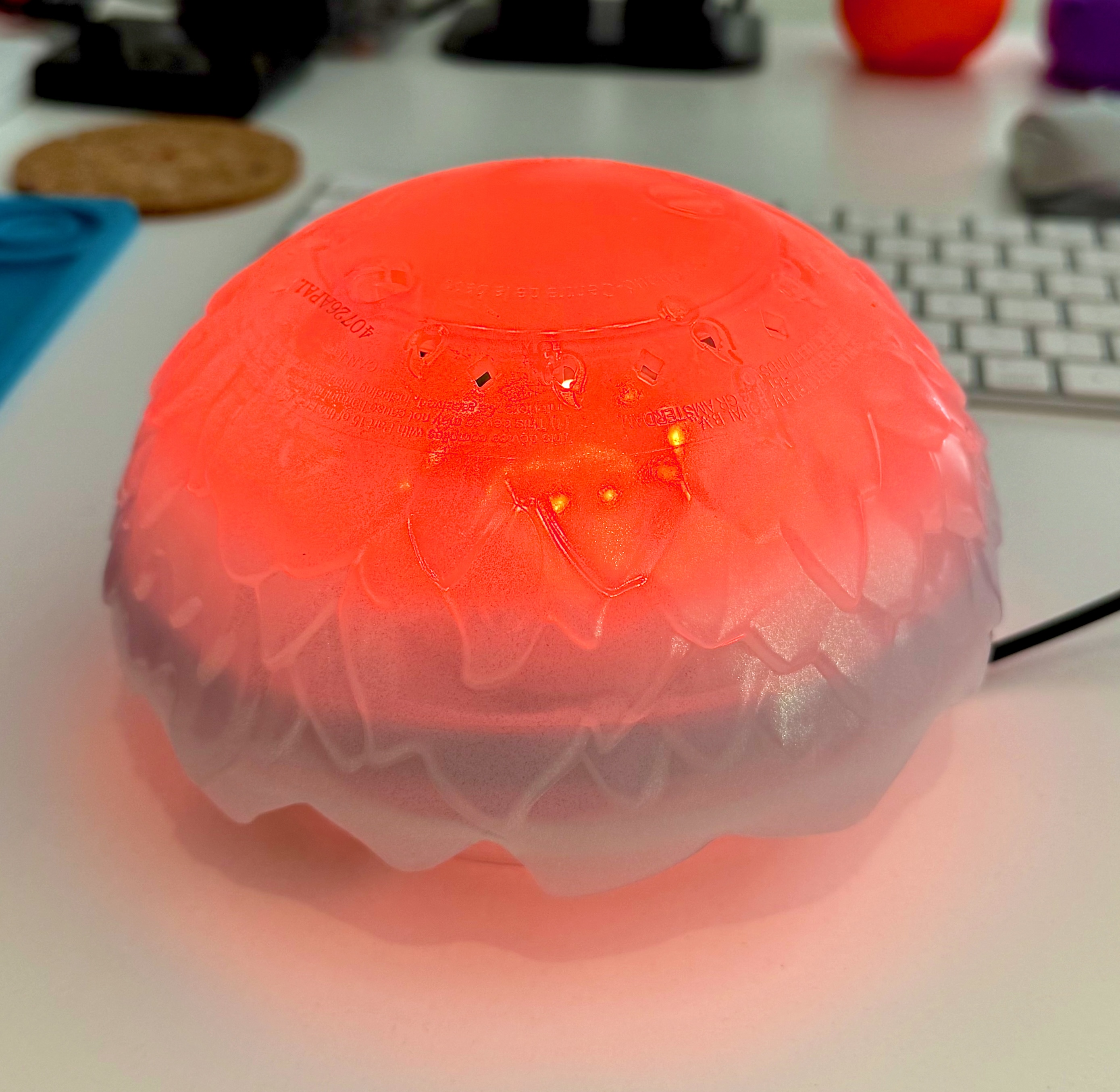 The finished lamp glowing red on a desk next to a keyboard