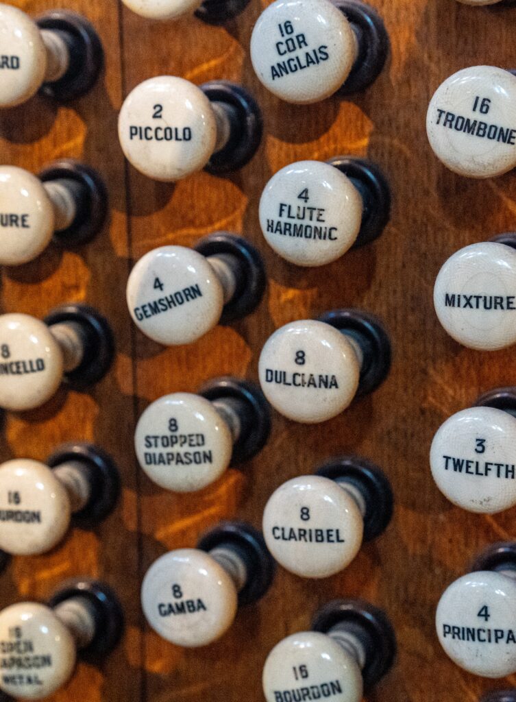 Rows of labelled organ stop knobs on a wooden console